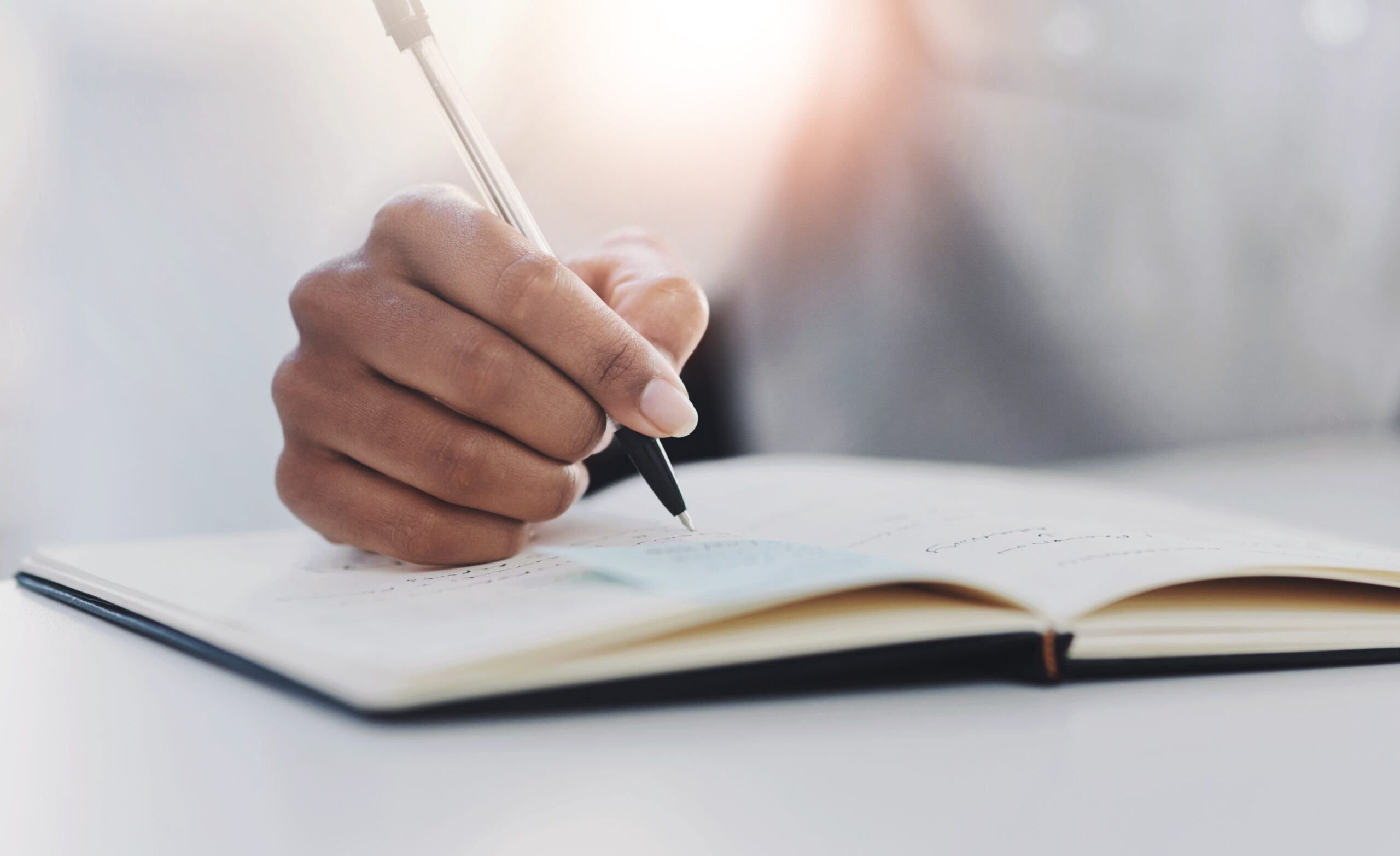 A hand holding a pen and writing a career plan in a notebook