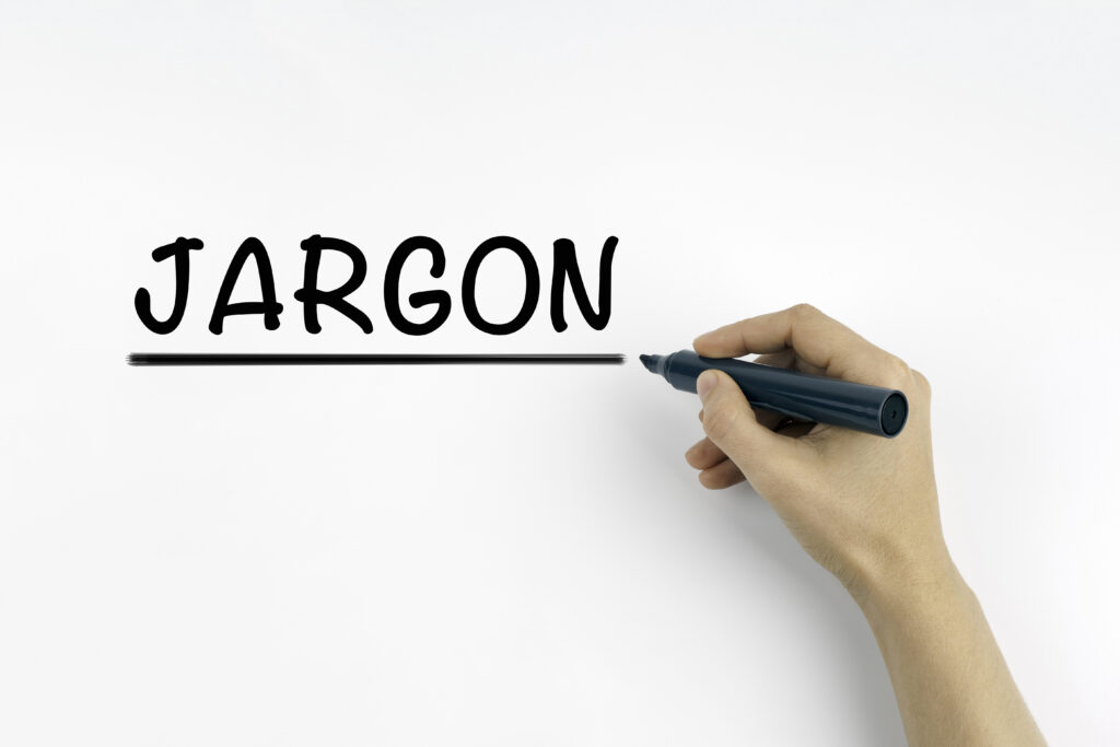 "Jargon" word written on a board with a hand holding a marker.