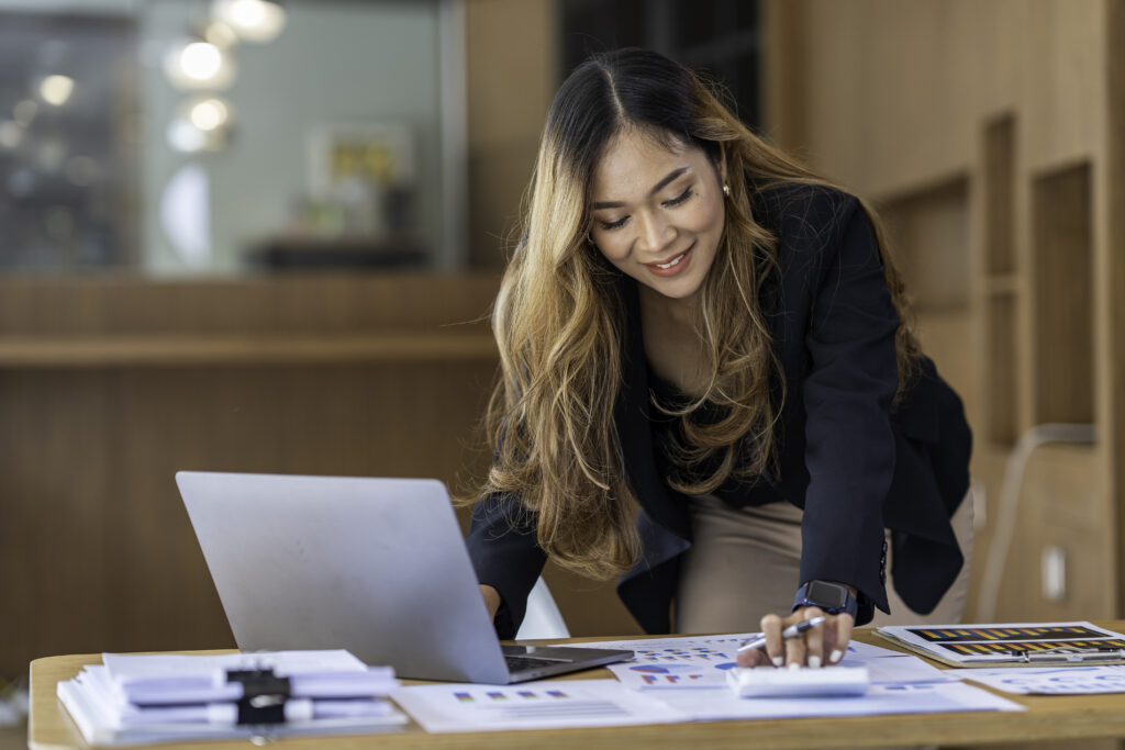 A brand ambassador working at a desk with a laptop and paper charts.