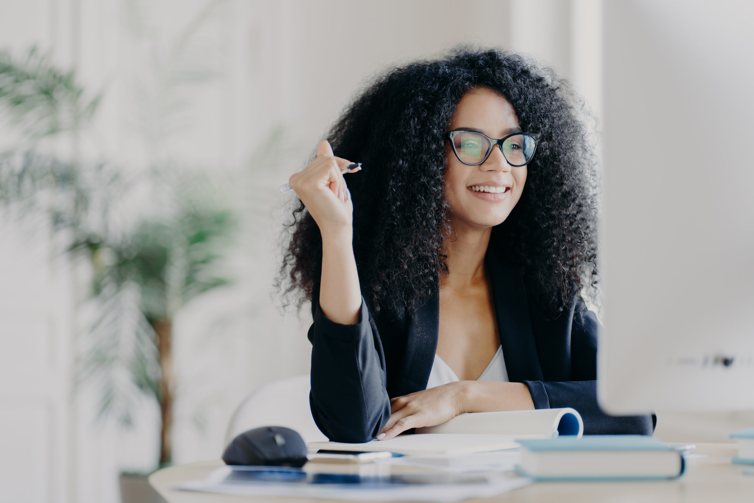 A smiling young woman sits at a desk working on her professional growth plan.